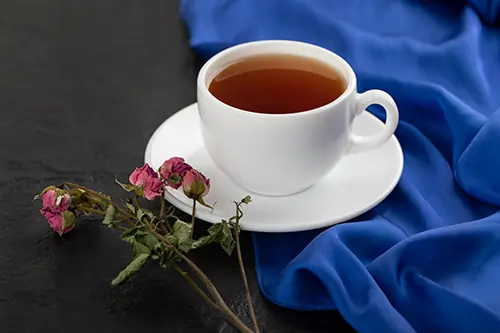 dried-roses-with-cup-hot-tea-black-table